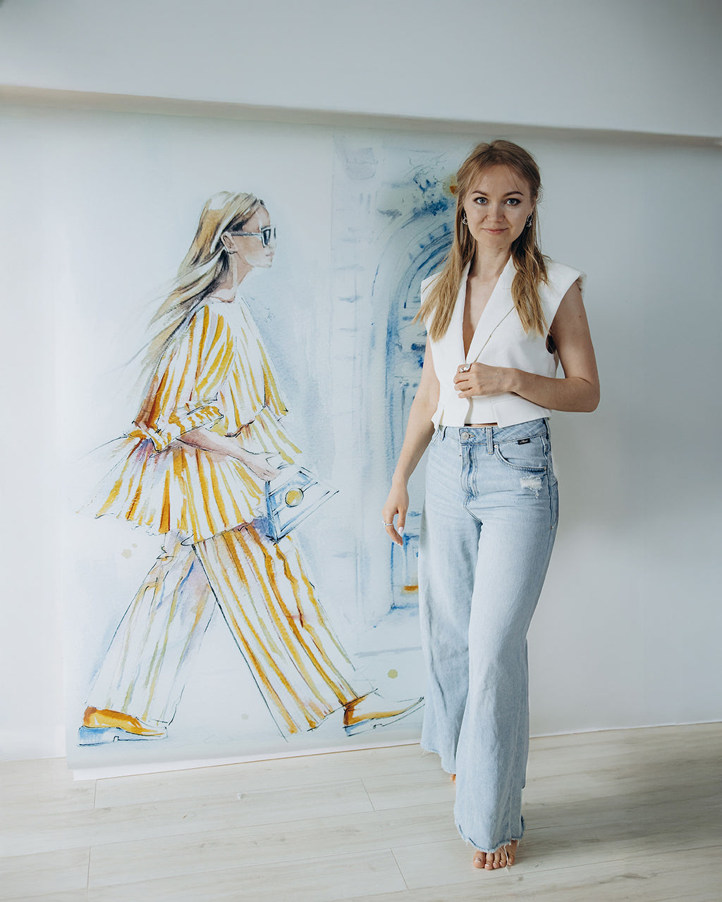 Exstra Large fashion illustration print titled "Golden Stripes stroll" displayed on the wall; artist beside for scale.