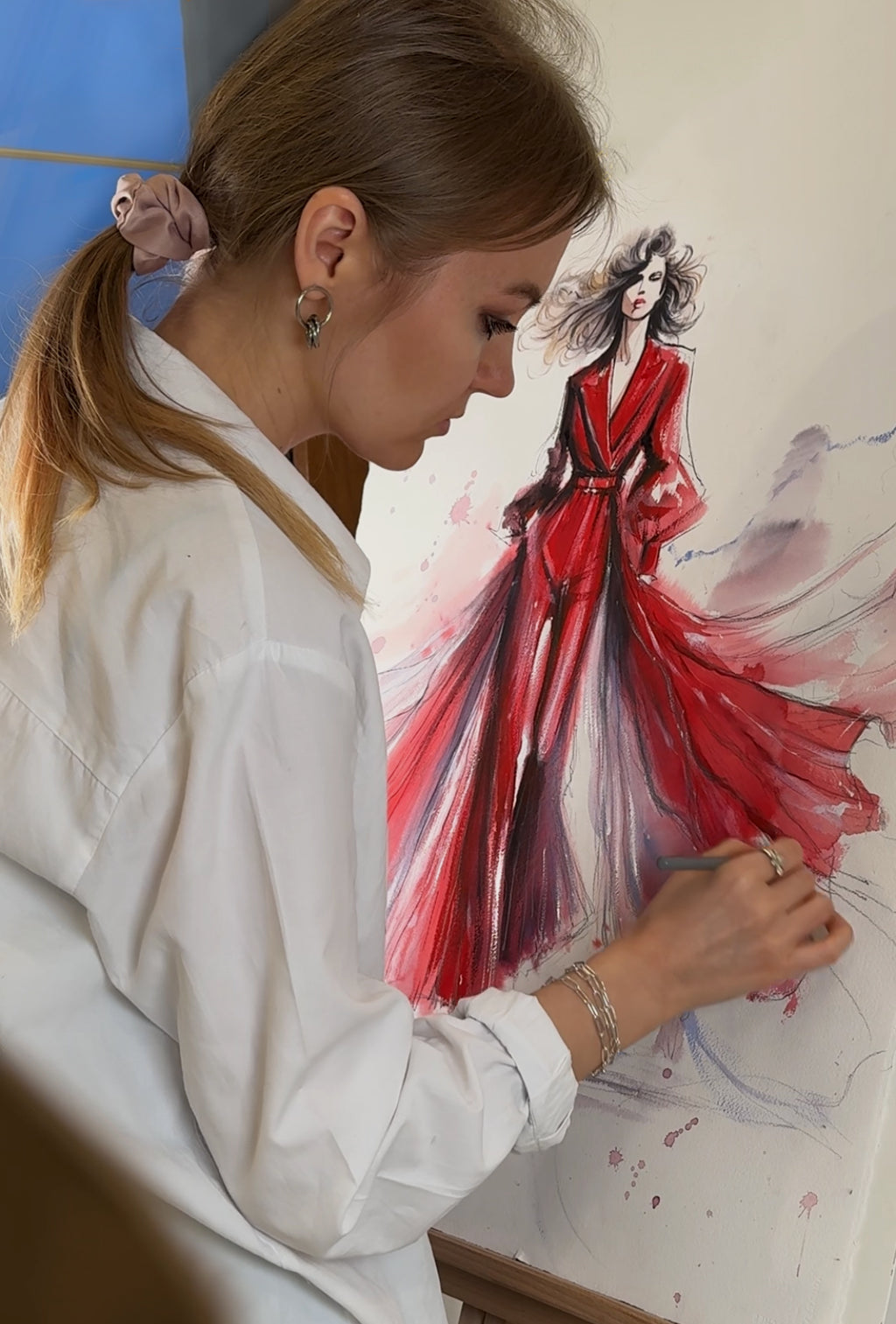 Woman painting a fashion illustration of a woman in a red dress.